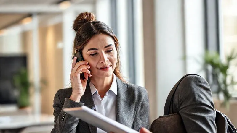 A photorealistic image of a professional travel agent, calm and focused, on a phone call, with a notepad and pen in hand, actively listening. The background is a clean, modern office setting, suggesting professionalism and efficiency. Soft, natural light illuminates the scene, 8K, cinematic lighting, sharp focus, depth of field, professional photography. A photorealistic image of a professional travel agent, calm and focused, on a phone call, with a notepad and pen in hand, actively listening. The background is a clean, modern office setting, suggesting professionalism and efficiency. Soft, natural light illuminates the scene, 8K, cinematic lighting, sharp focus, depth of field, professional photography.