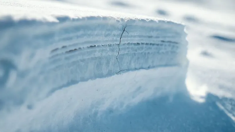 A photorealistic image of a highly detailed cross-section of a snowpack, showing distinct layers of varying crystal types and densities, with a faint crack line indicating a weak layer. Cinematic lighting, sharp focus on the snow layers, depth of field blurring the surrounding snow, 8K hyper-detailed, professional photography, shot on a high-end DSLR. A photorealistic image of a highly detailed cross-section of a snowpack, showing distinct layers of varying crystal types and densities, with a faint crack line indicating a weak layer. Cinematic lighting, sharp focus on the snow layers, depth of field blurring the surrounding snow, 8K hyper-detailed, professional photography, shot on a high-end DSLR.