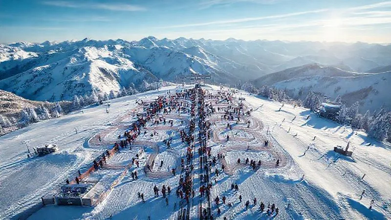 A photorealistic aerial view of a modern ski lift queue designed with intelligent maze barriers, clear signage for different skier groups, and efficient flow, set against a snowy mountain backdrop, 8K, cinematic lighting, sharp focus on the queue layout, depth of field blurring the distant peaks, shot on a high-end DSLR.