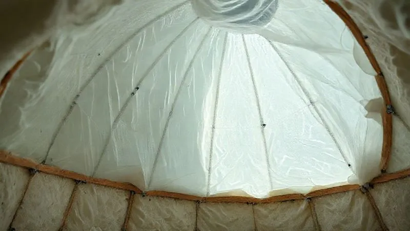 A photorealistic close-up view inside a geodome under construction, showing a translucent vapor barrier being meticulously installed over an insulation layer, with seams expertly taped. The scene emphasizes precision and detail in building envelope integrity. professional photography, 8K, cinematic lighting, sharp focus, depth of field, shot on a high-end DSLR A photorealistic close-up view inside a geodome under construction, showing a translucent vapor barrier being meticulously installed over an insulation layer, with seams expertly taped. The scene emphasizes precision and detail in building envelope integrity. professional photography, 8K, cinematic lighting, sharp focus, depth of field, shot on a high-end DSLR