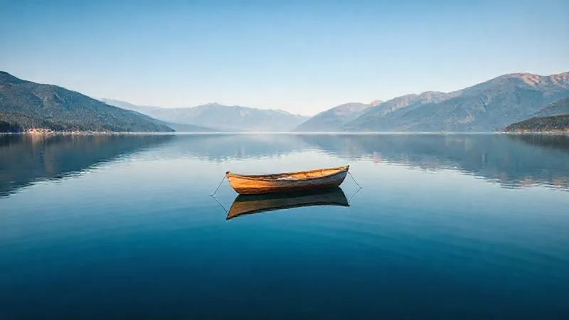 A photorealistic image of a calm, serene lake reflecting a clear blue sky and mountains. A single, small, traditional wooden rowboat is gently floating in the center, perfectly still, symbolizing quietude and undisturbed thought. The lighting is soft and natural, evoking a sense of deep peace. Professional photography, 8K, cinematic lighting, sharp focus on the boat and reflection, depth of field blurring the distant shore, shot on a high-end DSLR. A photorealistic image of a calm, serene lake reflecting a clear blue sky and mountains. A single, small, traditional wooden rowboat is gently floating in the center, perfectly still, symbolizing quietude and undisturbed thought. The lighting is soft and natural, evoking a sense of deep peace. Professional photography, 8K, cinematic lighting, sharp focus on the boat and reflection, depth of field blurring the distant shore, shot on a high-end DSLR.