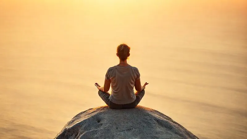 photorealistic, professional photography, 8K, cinematic lighting, sharp focus, depth of field, shot on a high-end DSLR. A solo traveler, a person in comfortable, practical clothing, sitting cross-legged on a smooth rock overlooking a vast, calm ocean at sunset. Their eyes are closed, hands resting on their knees in a meditative pose. The warm, golden light casts a serene glow, and the gentle waves are barely visible, emphasizing tranquility and deep introspection. The scene exudes peace and mental clarity. photorealistic, professional photography, 8K, cinematic lighting, sharp focus, depth of field, shot on a high-end DSLR. A solo traveler, a person in comfortable, practical clothing, sitting cross-legged on a smooth rock overlooking a vast, calm ocean at sunset. Their eyes are closed, hands resting on their knees in a meditative pose. The warm, golden light casts a serene glow, and the gentle waves are barely visible, emphasizing tranquility and deep introspection. The scene exudes peace and mental clarity.