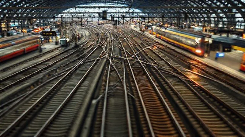 photorealistic, professional photography, 8K, cinematic lighting, sharp focus, depth of field, shot on a high-end DSLR. A complex network of European train tracks converging at a bustling station, with blurred lines of light representing fast-moving trains, symbolizing the intricate and sometimes confusing nature of the European railway system. A digital overlay of reservation symbols and 'X' marks subtly indicates challenges. photorealistic, professional photography, 8K, cinematic lighting, sharp focus, depth of field, shot on a high-end DSLR. A complex network of European train tracks converging at a bustling station, with blurred lines of light representing fast-moving trains, symbolizing the intricate and sometimes confusing nature of the European railway system. A digital overlay of reservation symbols and 'X' marks subtly indicates challenges.