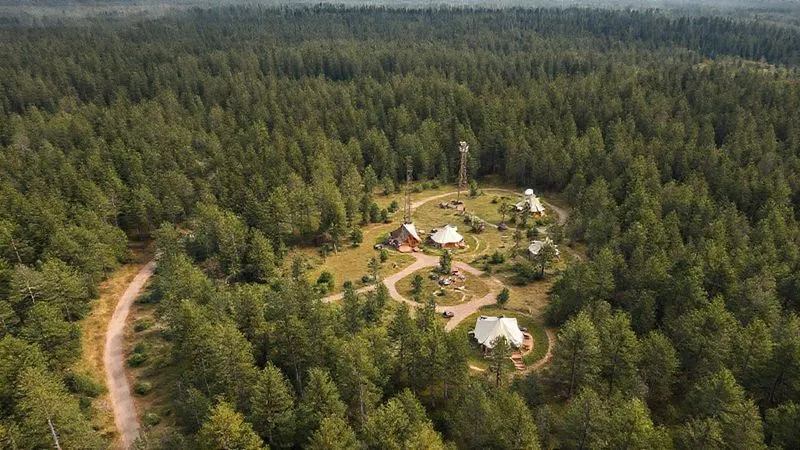 Aerial photorealistic image of a well-designed remote glamping site nestled in a pristine forest, showcasing clear, winding pathways, discreet emergency access roads, and a small, unobtrusive communication tower or satellite dish integrated into the landscape. The layout should appear logical and safe, with tents strategically placed away from obvious hazards. 8K, professional photography, cinematic lighting, sharp focus on the overall layout, depth of field blurring the distant tree line, shot on a high-end DSLR. Aerial photorealistic image of a well-designed remote glamping site nestled in a pristine forest, showcasing clear, winding pathways, discreet emergency access roads, and a small, unobtrusive communication tower or satellite dish integrated into the landscape. The layout should appear logical and safe, with tents strategically placed away from obvious hazards. 8K, professional photography, cinematic lighting, sharp focus on the overall layout, depth of field blurring the distant tree line, shot on a high-end DSLR.