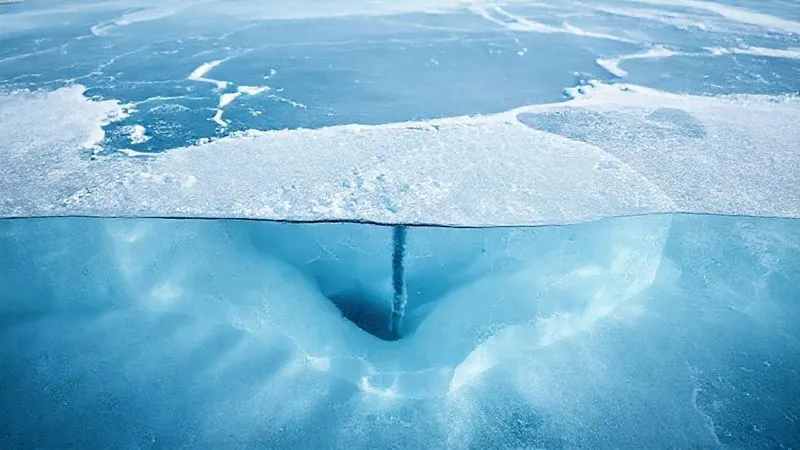 photorealistic, professional photography, 8K, cinematic lighting, sharp focus, depth of field, shot on a high-end DSLR. A cross-section view of a frozen lake, clearly illustrating varying ice thicknesses due to hidden underwater currents, snow cover, and a thermal spring. The ice shows different shades of blue and white, with thin, translucent areas contrasting with thicker, opaque sections. A small ice auger is partially visible, indicating measurement. photorealistic, professional photography, 8K, cinematic lighting, sharp focus, depth of field, shot on a high-end DSLR. A cross-section view of a frozen lake, clearly illustrating varying ice thicknesses due to hidden underwater currents, snow cover, and a thermal spring. The ice shows different shades of blue and white, with thin, translucent areas contrasting with thicker, opaque sections. A small ice auger is partially visible, indicating measurement.