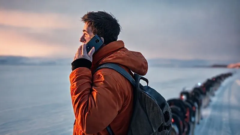 Photorealistic, professional photography of a musher standing next to their sled, holding a satellite phone to their ear, looking out at a vast, snow-covered landscape. A faint signal light from a SPOT device is visible on their pack. Cinematic lighting, sharp focus on the musher's determined expression, depth of field showing the scale of the wilderness. 8K hyper-detailed, shot on a high-end DSLR, conveying a sense of urgency and preparedness. Photorealistic, professional photography of a musher standing next to their sled, holding a satellite phone to their ear, looking out at a vast, snow-covered landscape. A faint signal light from a SPOT device is visible on their pack. Cinematic lighting, sharp focus on the musher's determined expression, depth of field showing the scale of the wilderness. 8K hyper-detailed, shot on a high-end DSLR, conveying a sense of urgency and preparedness.