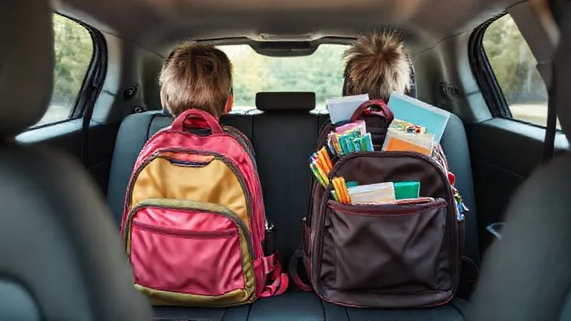 A neat and organized car backseat with two individual, colorful children's backpacks filled with age-appropriate quiet toys, books, and drawing supplies. The items are partially visible, suggesting readiness for a long journey. Photorealistic, professional photography, 8K, cinematic lighting, sharp focus, depth of field, shot on a high-end DSLR, inviting and calming atmosphere.