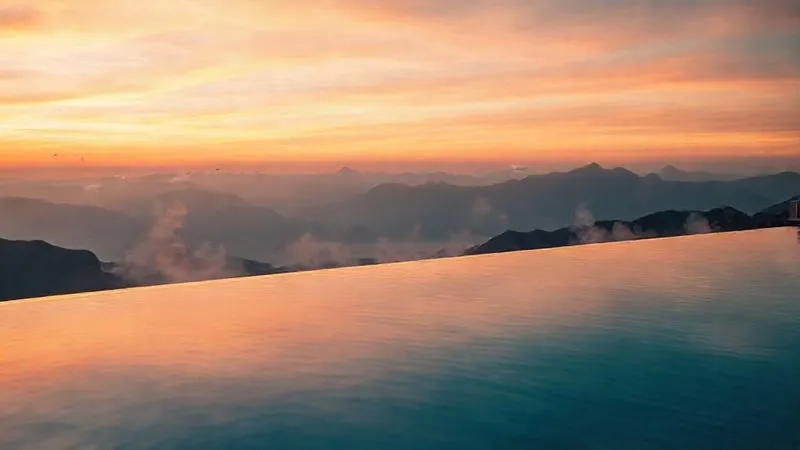 Photorealistic professional photography of a luxury wellness resort's infinity pool overlooking a serene mountain range at sunrise. The water is perfectly still, reflecting the vibrant sky, with steam gently rising. Sharp focus on the tranquil scene, depth of field blurring distant peaks. 8K hyper-detailed, cinematic lighting. Photorealistic professional photography of a luxury wellness resort's infinity pool overlooking a serene mountain range at sunrise. The water is perfectly still, reflecting the vibrant sky, with steam gently rising. Sharp focus on the tranquil scene, depth of field blurring distant peaks. 8K hyper-detailed, cinematic lighting.